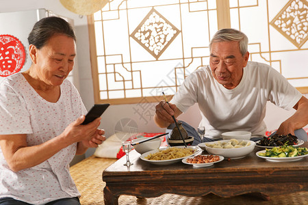 老年夫妇在家里吃饭看手机图片素材