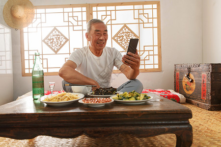 老年人坐在家里吃饭看手机高清图片