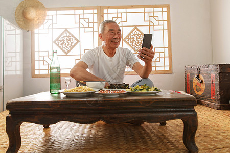 老年人坐在家里吃饭看手机图片素材