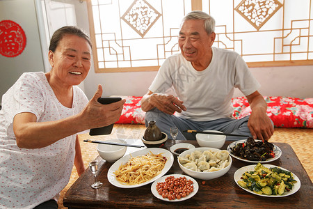 老年夫妇在家里吃饭看手机图片素材