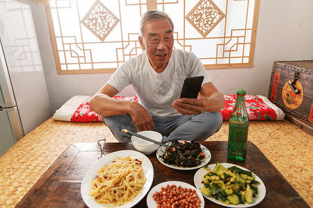 老年人坐在家里吃饭看手机图片素材