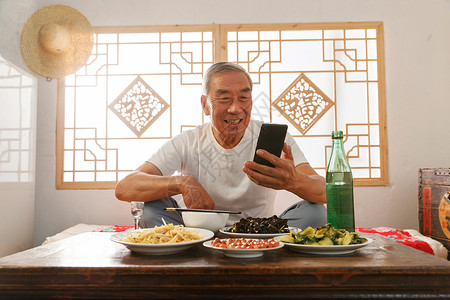互联网餐饮老年人坐在家里吃饭看手机背景