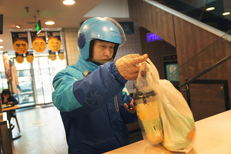 外卖员在餐厅取餐安全帽高清图片素材