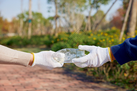 环保志愿者递塑料瓶特写地球日高清图片素材