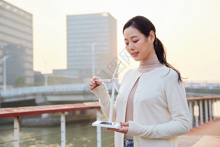 青年女性手拿太阳能风车模型高清图片