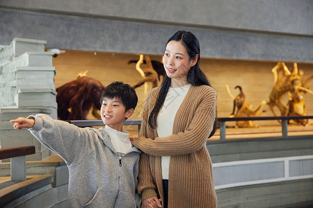 学生参观博物馆年轻妈妈带儿子参观自然博物馆背景