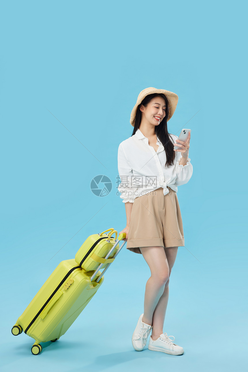 外出旅游拉行李箱的青年女子看手机图片