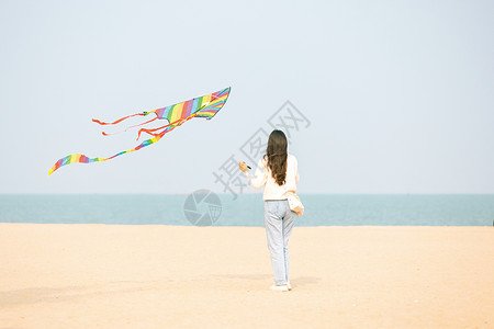 在海边放风筝的女生背影背景图片