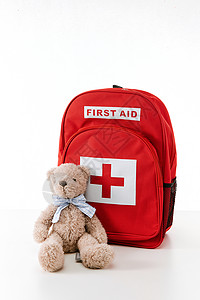 棕色书包旅游包医用急救书包和玩具熊背景