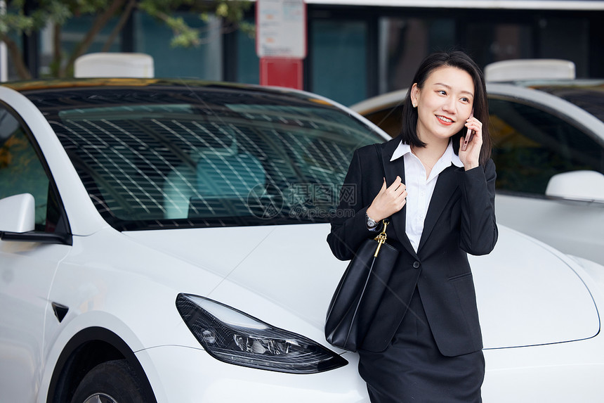 在新能源汽车前打电话的商务女性图片