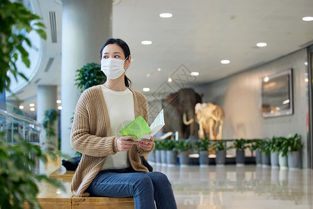 戴口罩的女性手拿导览手册图片