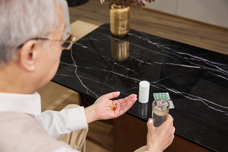 手握药瓶在家吃药的老年人背景
