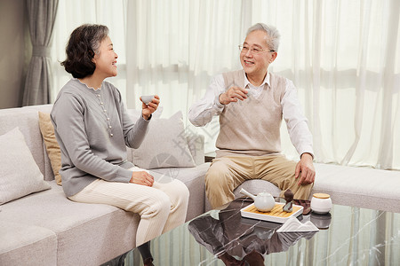 坐在客厅喝茶的老年人背景图片