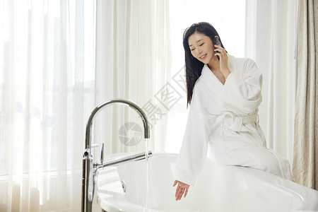 年轻浴袍美女浴室打电话背景图片