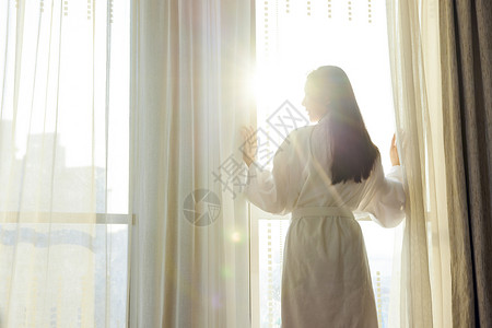 美女酒店早晨起床拉开窗帘背影背景图片
