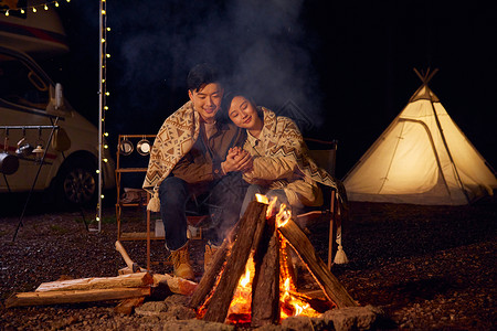 年轻夫妻户外露营烤火取暖图片