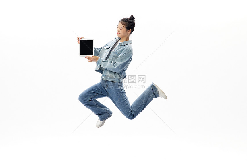 手拿平板电脑的活力女性悬浮跳跃图片