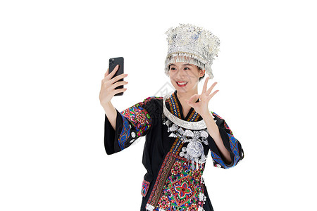 对着手机做ok手势的苗族女性背景图片