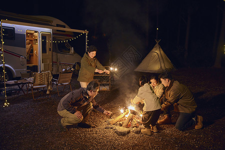 夜晚户外房车露营篝火的大家庭图片
