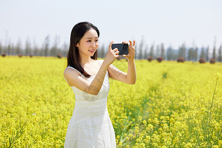 使用手机拍油菜花海美景的女性高清图片