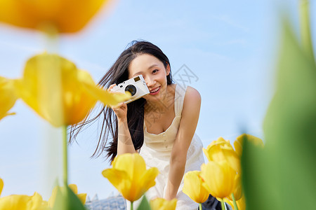 戴着相机出游的女孩郁金香前景手拿照相机的美女背景