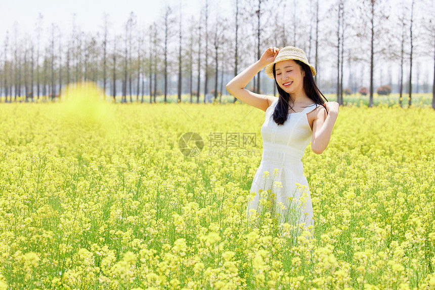 少女站在油菜花田里享受阳光图片