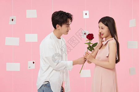 情侣卡片粉色背景下男生给女生送玫瑰花背景