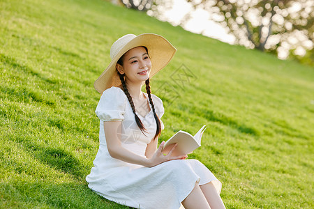 草帽女生草坪上看书的文艺女性背景
