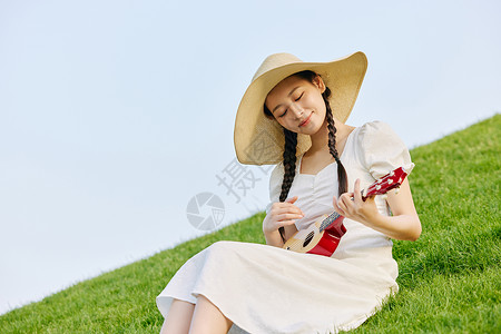 女生弹琴草坪上的文艺女性弹尤克里里背景