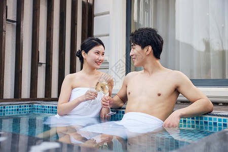 度假酒店泡温泉干杯的年轻情侣图片