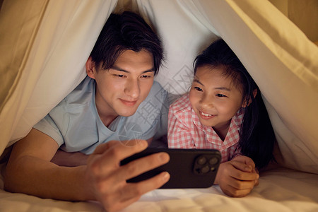 父亲和女儿藏在被窝里看手机图片