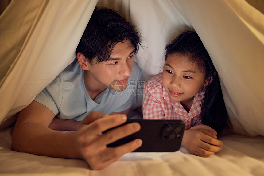 父亲和女儿藏在被窝里玩手机图片