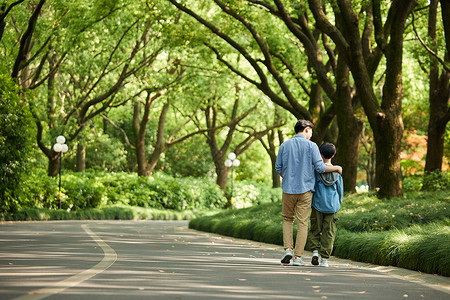 孩子在公园父子二人在公园里散步背影背景
