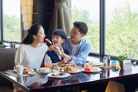 一家人在餐厅互相喂食食品高清图片素材