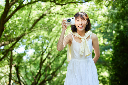 女生夏日外出散步用照相机拍照图片