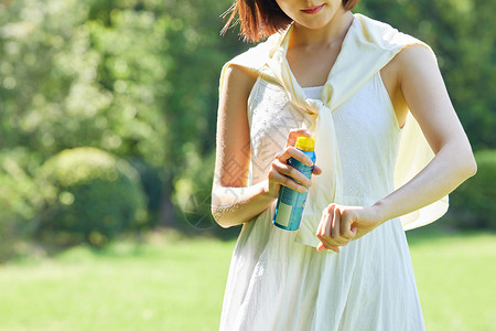 女性室外使用防晒喷雾特写图片素材