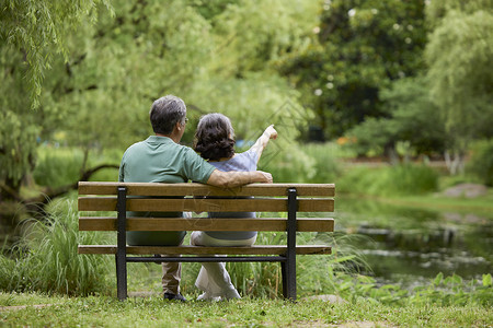 老年夫妇坐在公园长椅欣赏风景背景图片