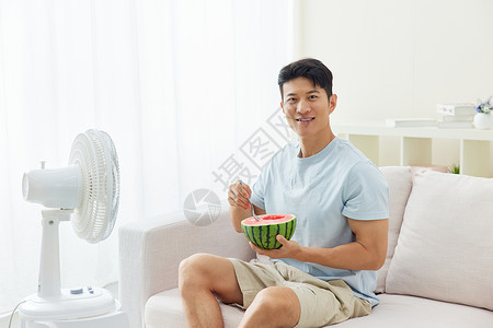 居家男性吃西瓜吹风扇夏天高清图片素材