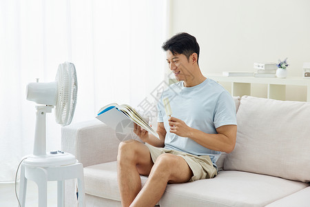 男人吹着风扇看书吃冷饮夏日高清图片素材