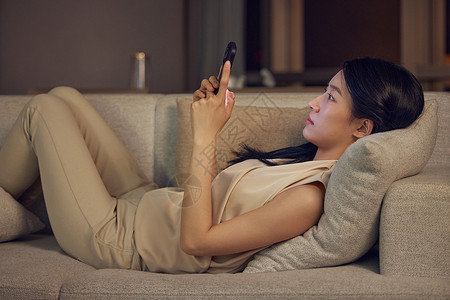 躺在沙发上玩手机的女性形象背景图片