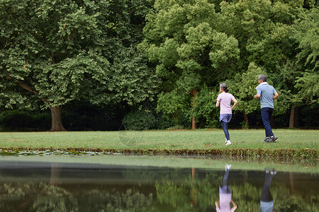 绿色跑步河边草坪上跑步的老夫妻背景