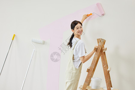 女主人将墙面粉刷成粉色背景图片