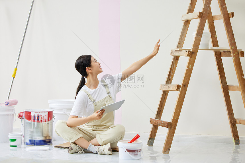 女子盘坐在墙前构思房屋装修图片