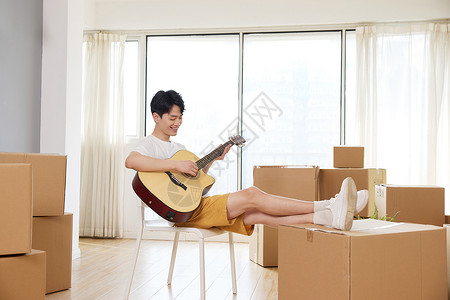 双脚架在纸箱上弹奏吉他的男人高清图片