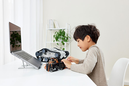 电脑桌前组装机器的小男孩背景图片