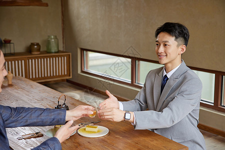 商务男士碰杯商务男士喝茶吃点心背景