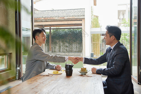 商务饭局中洽谈握手的男人图片