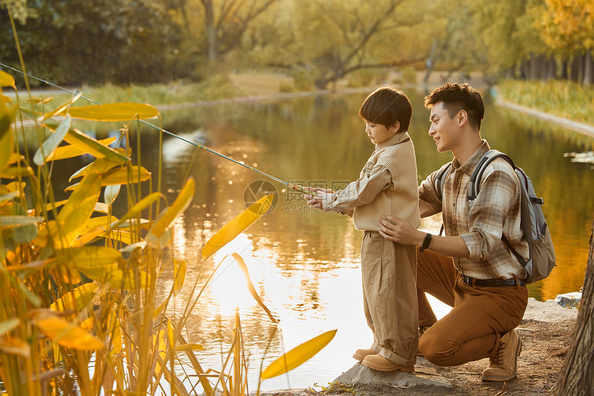 父亲教小男孩在河边钓鱼图片