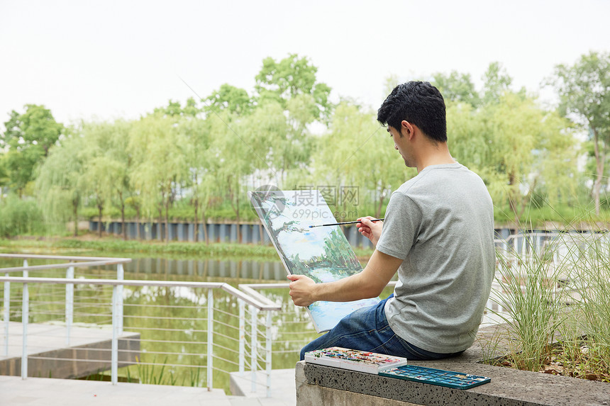 手拿画板户外写生的男性图片