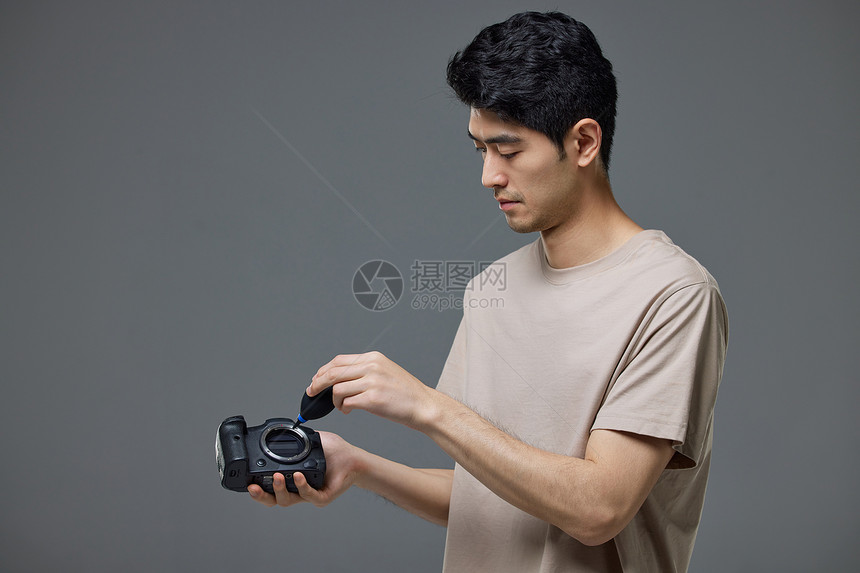 摄影师使用气吹给照相机清灰尘图片